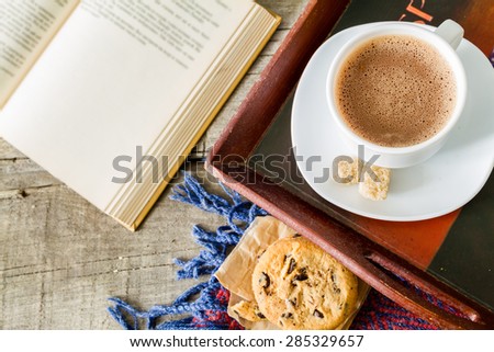 Autumn lifestyle - hot chocolate, chocolate chip cookies, old book, tray, warm blanket, rustic wood background, top view