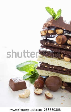 Chocolate background - different types of chocolate, cookies, candies, nuts, mint, cherry, white wood background
