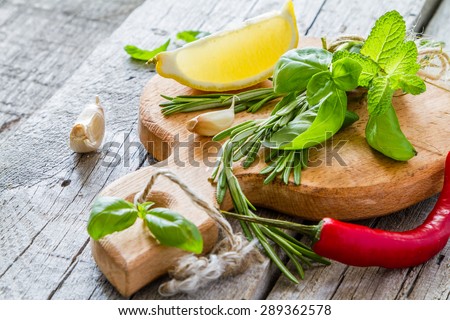 Herbs background - rosemary, basil, mint, lemon, chili, garlic, pepper on wood board, rustic wood background, closeup
