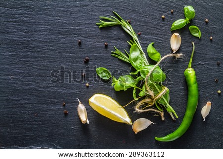 Herbs background - rosemary, basil, mint, lemon, chili, garlic, pepper, dark stone background, top view