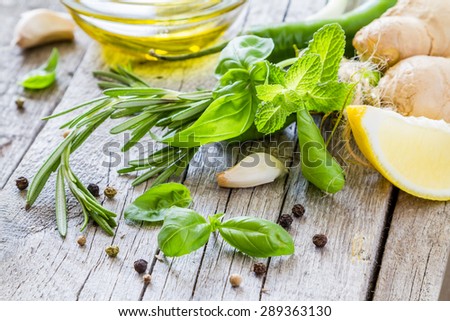 Herbs background - rosemary, basil, mint, ginger, lemon, oil, chili, garlic, pepper, rustic wood background, closeup
