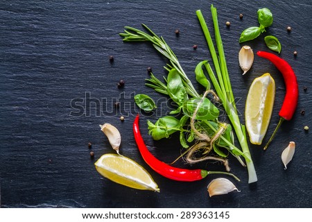Herbs background - rosemary, basil, mint, lemon, chili, garlic, pepper, dark stone background, top view