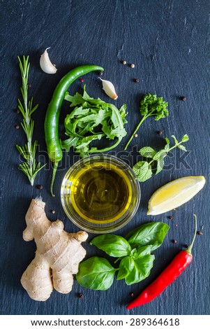Herbs background - chili, lemon, mint, parsley, basil, garlic, ginger, rosemary,  dark stone background, top view