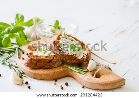 Garlic bread - baguette slices, garlic butter, herbs, wood board, white wood background