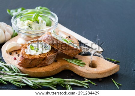 Garlic bread - baguette slices, garlic butter, herbs, wood board, dark, stone background