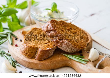 Garlic bread - baguette slices, garlic butter, herbs, wood board, white wood background