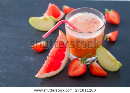 Apple, strawberry and grapefruit smoothie and ingredients, dark stone background