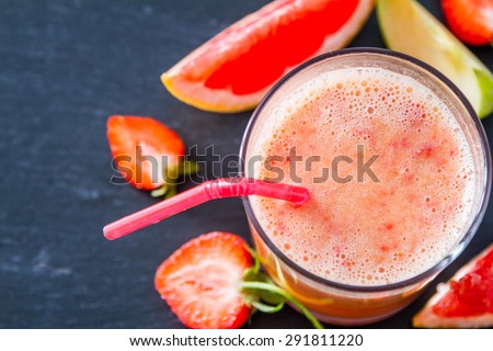 Apple, strawberry and grapefruit smoothie and ingredients, dark stone background, top view