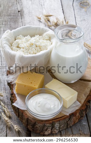 Fresh dairy products (milk, cottage cheese, cheese, sour cream, butter), wheat, rustic wood background