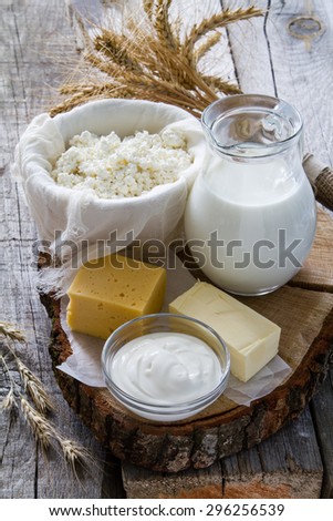 Fresh dairy products (milk, cottage cheese, cheese, sour cream, butter), wheat, rustic wood background