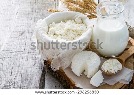 Fresh dairy products (milk, cottage cheese), wheat, rustic wood background