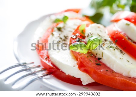 Insalata caprese - tomato, mozzarella, basil, olive oil, white plate, white wood background