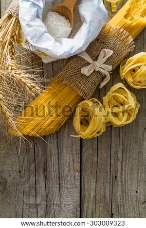 Raw pasta, flour, wheat, rustic wood background, top view