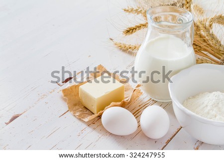 Ingredients for baking - milk butter eggs flour wheat, white wood background, copy space