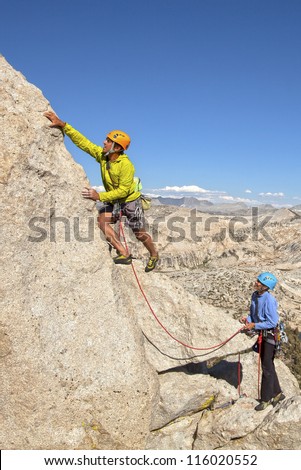 Climbing team ascending a challenging cliff.