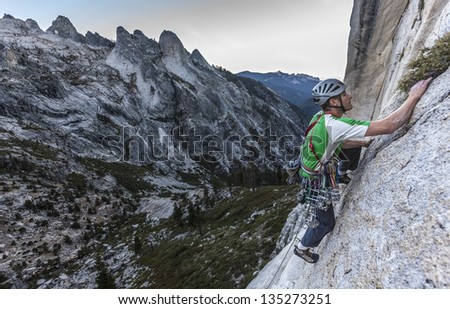 Rock climber struggles for his next grip on a challenging ascent.