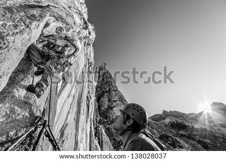 Team of climbers struggle up a steep and challenging rock spire.