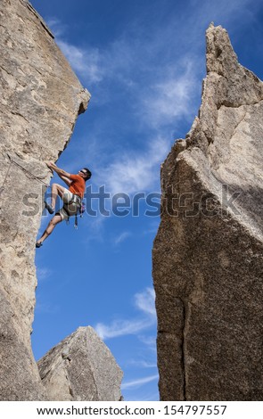 Rock climber clings to the edge of a challenging cliff in Joshua Tree National Park.