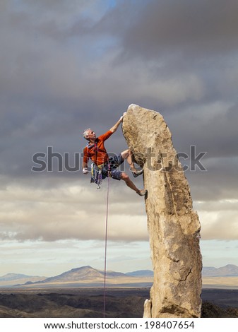 Climber struggles for his next grip on the edge of a challenging cliff Climber struggles for his next grip on the edge of a challenging cliff