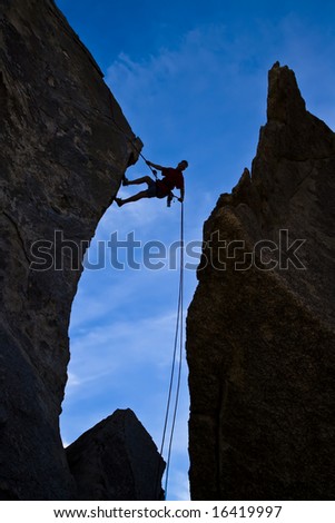 Rock climber rappelling down a sheer rock face in Joshua Tree National Park.