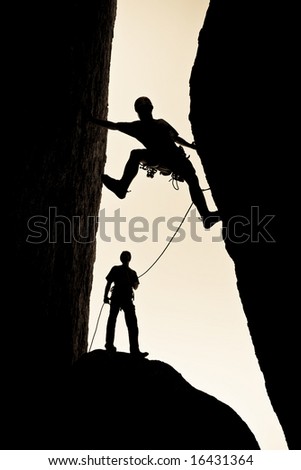 A team of rock climbers are silhouetted as they work their way up a chimney in Joshua Tree National Park.