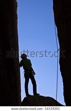 Rock climber silhouetted as he contemplates his route up a chimney in Joshua Tree National Park.