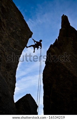 A rock climber is silhouetted against the evening sky as he rappels past an overhang in Joshua Tree National Park.
