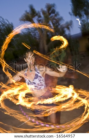 Hoop dancer performing with a fire-hoop, the hoop has six lighted wicks on the outside edge.