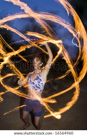 Hoop dancer performing with a fire-hoop, the hoop has six lighted wicks on the outside edge.