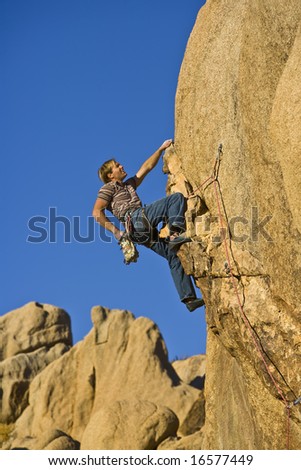 A rock climber clings to an overhanging rock face.