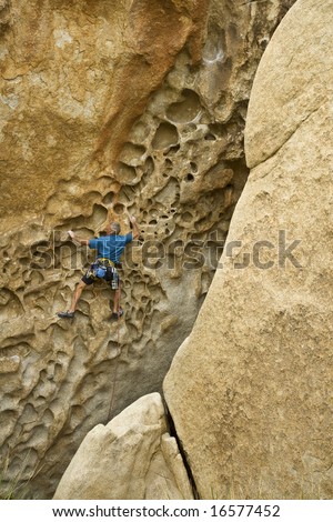 Rock climber clinging to a steep, rock face in the HIdden Valley area of Joshua Tree National Park.