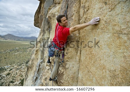 Rock climber reaching for his next hand hold, Joshua Tree National Park.