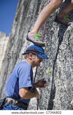 A rock climber using his partners head as a foothold in Yosemite National Park on a summer afternoon climbing adventure.