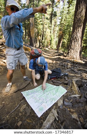 Two hikers consult their map along the trail in Yosemite National Park, California on a summer afternoon.