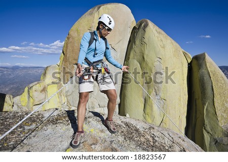 Climber beginning her descent from the summit of a rock spire in The Sierra Nevada Mountains, California, on a summer day.