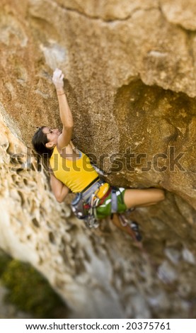 Female climber ascending a steep rock face in Joshua Tree National Park.