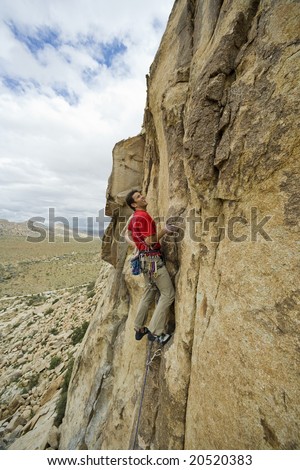 Climber clinging to rock face in Joshua Tree National Park, California.