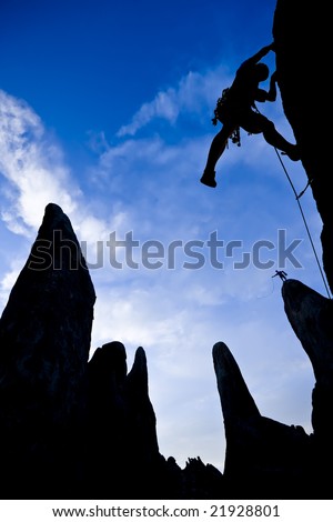 A climber ascends a rock spire, silhouetted against evening clouds in the Alabama Hills, below Mt. Whitney
