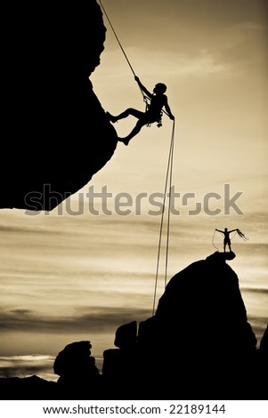 A climber is silhouetted as she rappels from the summit of a rock spire in The Sierra Nevada Mountains, California, after a successful ascent.