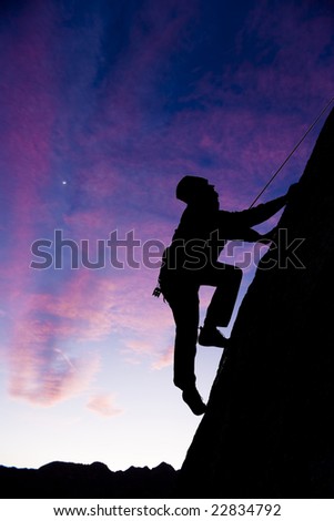A climber is silhouetted as he makes his way up a steep, sheer, rock face in The Sierra Nevada Mountains, California.