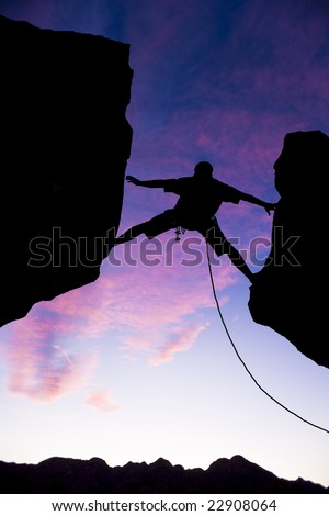 A climber is silhouetted as he reaches across a gap in the rock, in the Sierra Nevada  Mountains, California.