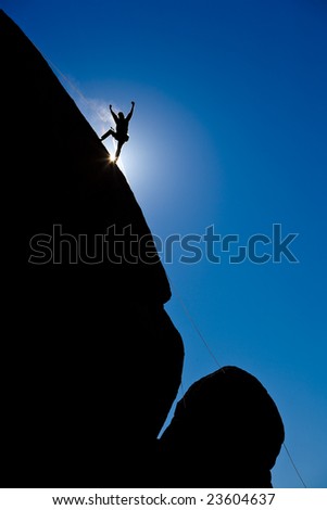 A climber is silhouetted as rappels down a steep rock face in the Sierra Nevada Mountains, California.