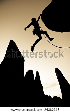 A climber dangles from the edge of an overhanging rock in The Sierra Nevada Mountains, California.