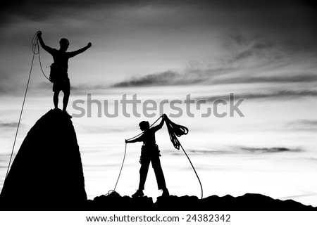 Team of climbers silhouetted as they coil ropes after reaching the summit of a rock pinnacle in The Sierra Nevada Mountains, California.