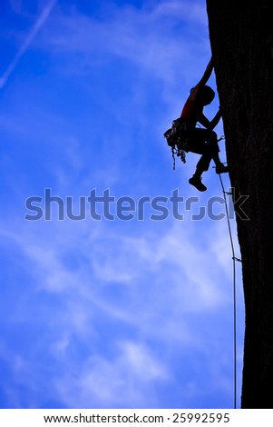 A climber is silhouetted as she clings to a steep rock face in Joshua Tree National Park, California.