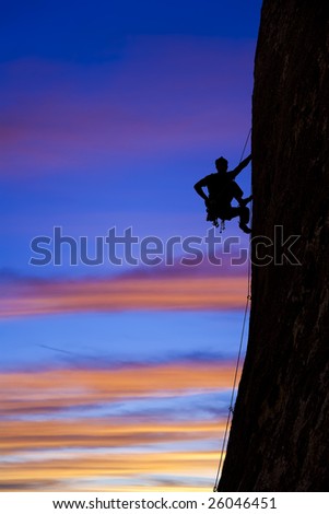 A climber is silhouetted as he clings to a steep rock face in Joshua Tree National Park, California.