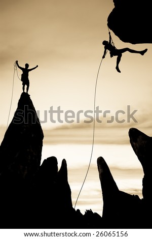 Team of rock climbers silhouetted on the summit,  dangle in midair rappelling from a rock spire in The Sierra Nevada Mountains.