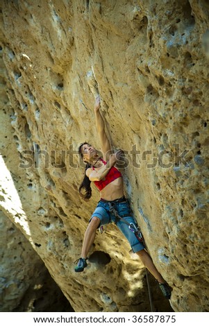 Female climber clinging to an overhanging rock face in Joshua Tree National Park. California.