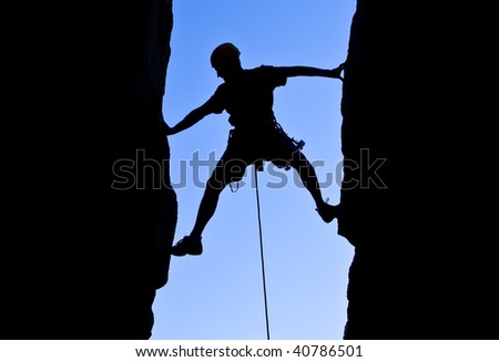 Rock climber silhouetted as he climbs up a chimney in Joshua Tree National Park, California.