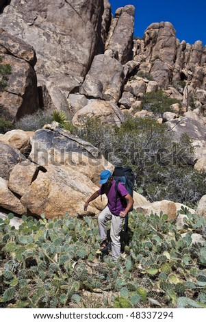 Hiker carefully takes his next step in the middle of a cactus patch.
